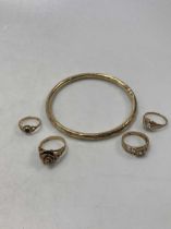 A hallmarked 9ct gold bangle, together with three hallmarked 9ct gold rings, and one ring stamped '