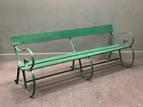 A late Victorian green painted wrought iron and wooden slatted garden bench on scrolled supports