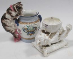 A Victorian ceramic white glazed cat playing on a pillow; together with a cat mounting an Italian