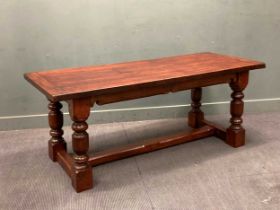 A 17th century style oak refectory table with cleated end top over turned legs joined by an H-