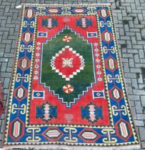 A geometric tribal rug, with red ground and blue border, 290 x 188cm