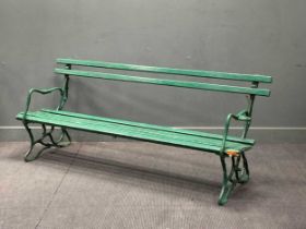 A Victorian green painted garden bench, the slatted back and seat raised on naturalustic wrought