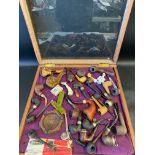 A table top display cabinet containing a collection of pipes and accessories etc.