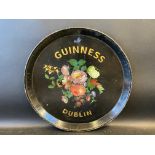 A circular papier mache tray with central floral display, bearing words for Guinness of Dublin 18"