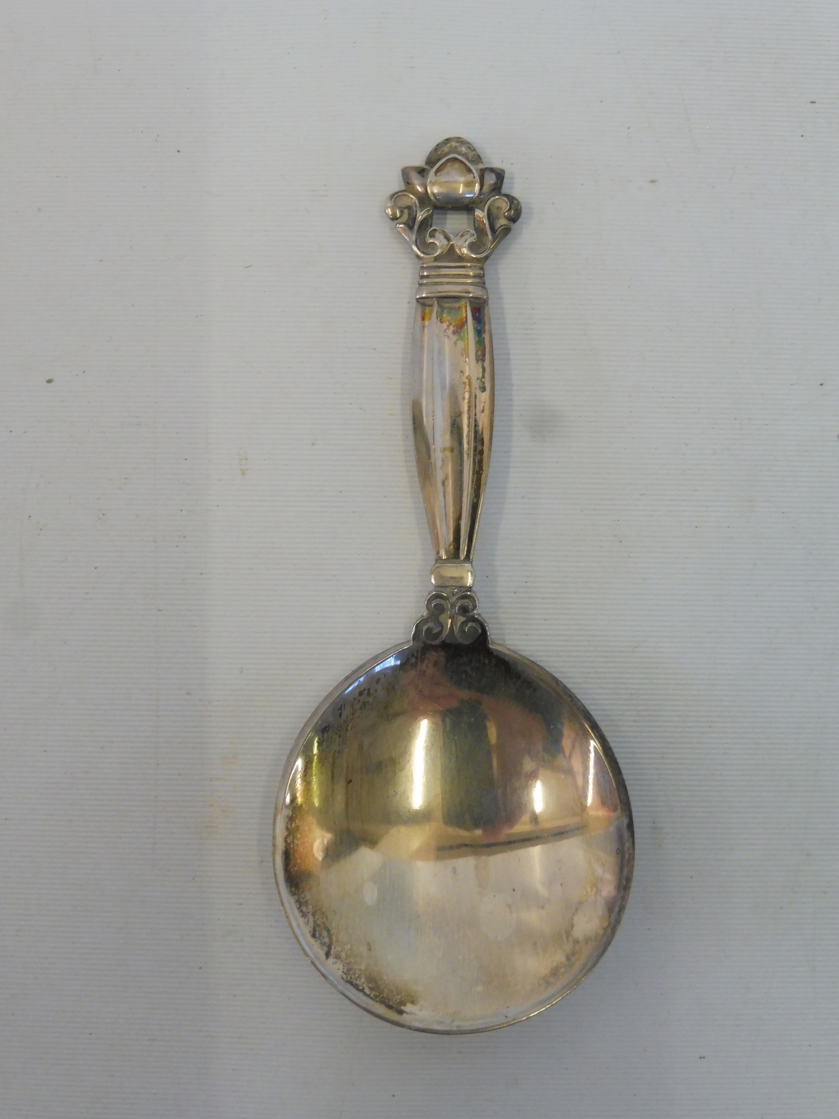 Georg Jensen: a caddy spoon with a foliate and scrolled finial.