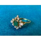 An emerald and diamond ring, two rectangular cut diamonds and 10 round brilliant cut plus an emerald