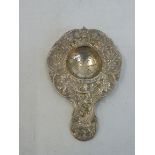 A silver tea strainer, embossed with cherubs, maker E.T.B., London 1901, F import mark, approx. 46.