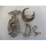 A marcasite encrusted lady's watch hanging from a bow brooch and two crescent-shaped brooches, one