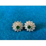 A pair of emerald and diamond stud earrings, two circular faceted cut emeralds and 40 round