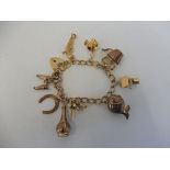 A 9ct gold charm bracelet with nine charms all hallmarked 9ct gold including a fish, a kettle, a