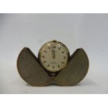 An unusual travelling clock, set within a silver plated and brass circular case, that opens to