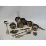 A pair of small silver circular salts; a silver tea strainer; a collection of four silver napkin