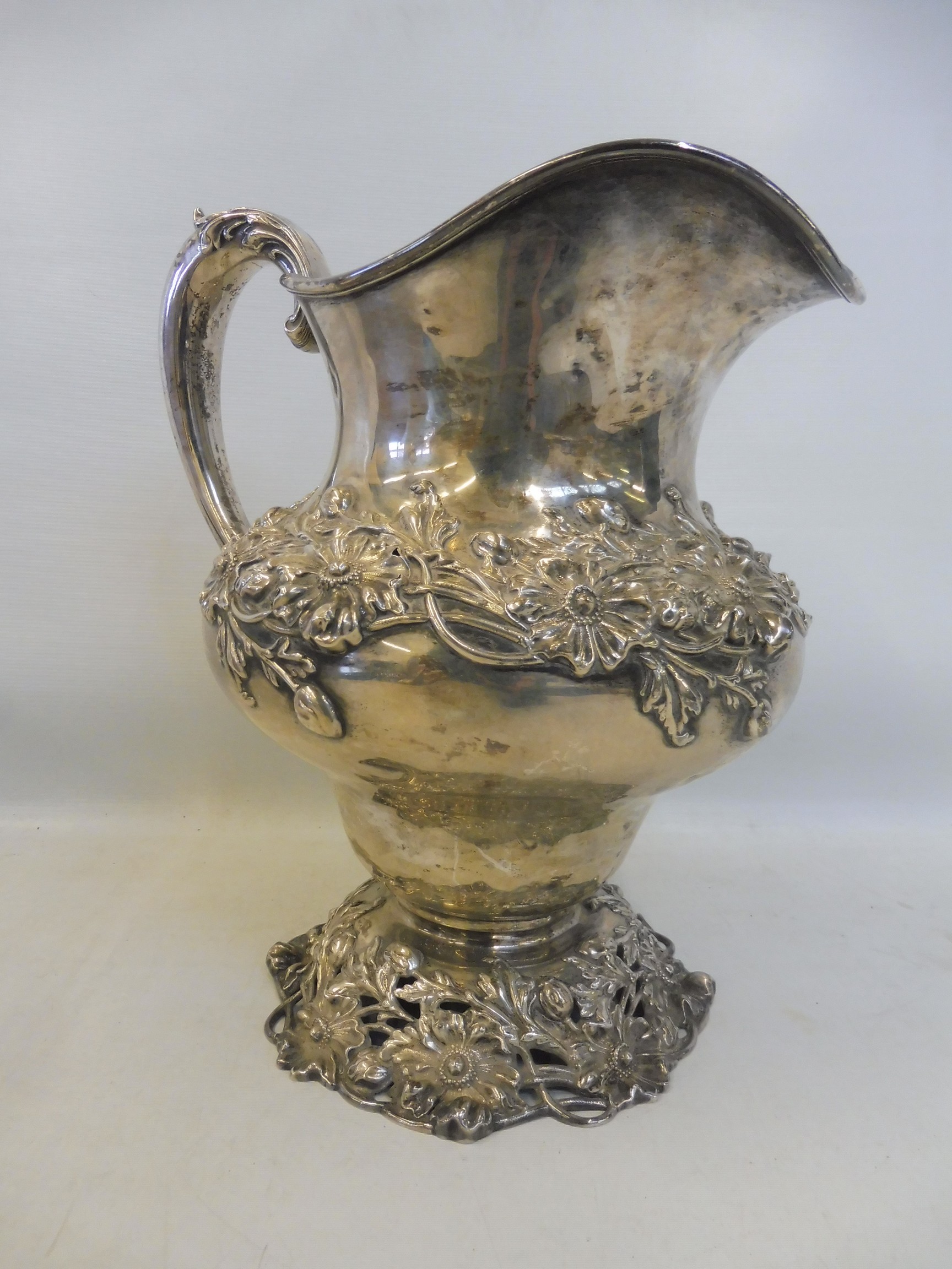 A large Sterling silver jug, with entwined floral design, raised on a pierced floral base, stamped