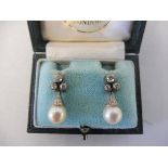 A pair of diamond and pearl earrings set with three stones presented in a Hennell Frazer & Haws,