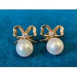 A pair 18ct gold pearl stud earrings - two teardrop shaped pearls hung from bows, set with a diamond