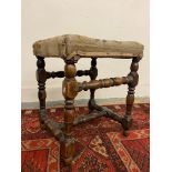 An early walnut stool, probably 18th Century with turned supports and stretchers, covered with a