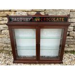 A Cadbury's Chocolate front opening two door cabinet, with carved frame, etched glass doors