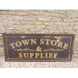 A wooden shop advertising sign, bearing the words 'Town Store & Supplies', 67 3/4 x 28 3/4".