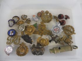 A box of brass and enamel military badges, whistle etc.