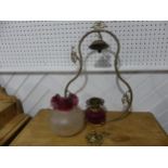 A Victorian hanging brass Oil Lamp, having a cranberry glass font and shade, one brass ornament