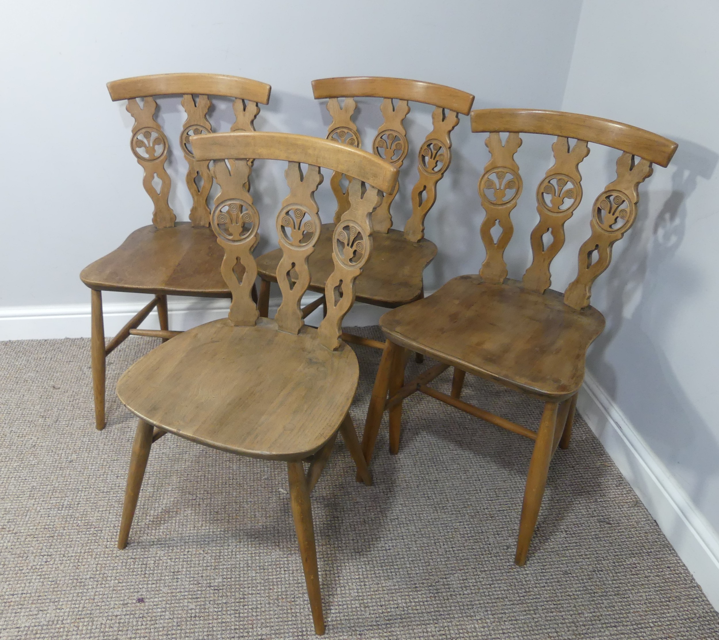 A set of four vintage ash kitchen chairs, all with carved backs, one chair has a different shaped