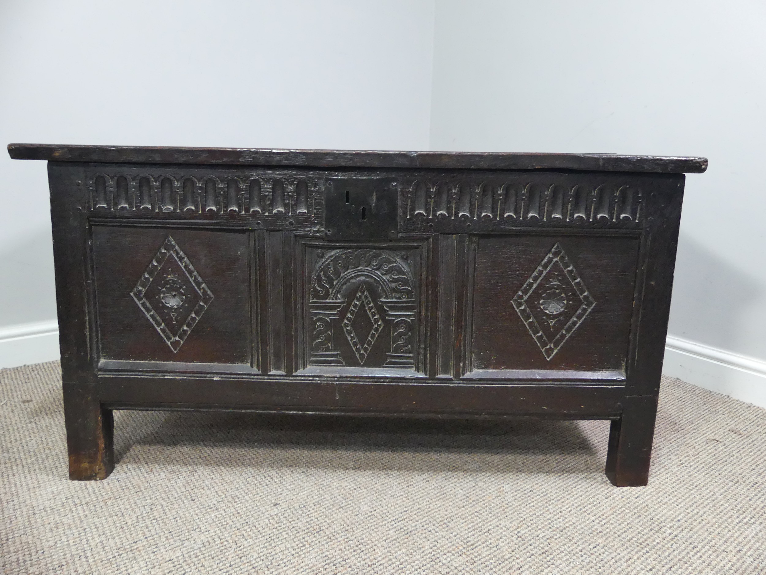 A 17th century oak three panel Coffer, the front with carved panels below a carved frieze, on square