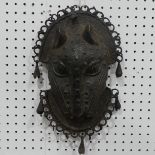 Tribal art; a Benin bronze leopard mask with punched and raised decoration, edged with ring loops