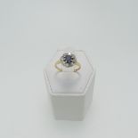 A sapphire and diamond cluster Ring, the central circular facetted sapphire 4.8mm diameter, claw set