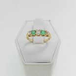 A graduated emerald and diamond five stone Ring, the central old cut stone approx. 0.16ct, with an