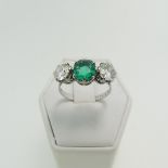 An emerald and diamond three stone Ring, the central octagonal step cut emerald, approx 1.2ct,