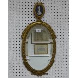 A gilt framed oval mirror, with a black Limoges plaque and beveled glass, H 63 cm x W 31 cm,