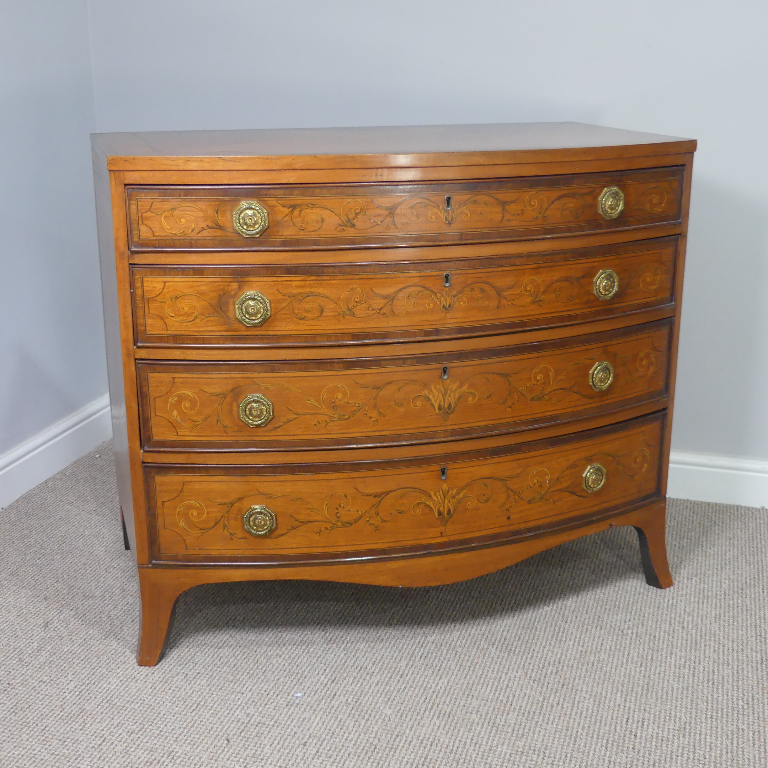 An Edwardian Sheraton Revival inlaid mahogany bow front Chest of Drawers, note damage to one side
