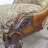 A Victorian carved upholstered nursing chair, with floral carved press rail upon cabriole legs and