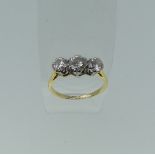 A three stone diamond Ring, the centre circular stone approx 0.63ct, with a smaller stone one either