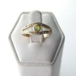 A peridot and diamond Ring, the split front with central collet set peridot with a row of diamond