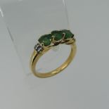 A three stone emerald Ring, the circular facetted stones approx 4.4mm diameter, with two diamond