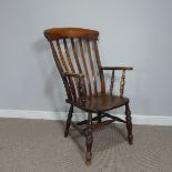 An antique stained ash and elm Windsor stick back elbow Chair, raised on turned legs and stretchers,