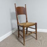 An Arts & Crafts style oak side chair with rush seat in the manner of William Birch, supported by