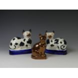 A pair of antique Staffordshire Cats, modelled in recumbent pose on blue cushion, together with a
