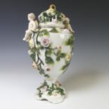 A Sitzendorf porcelain figural Urn, the relief work floral encrusted body with cherubic figures