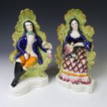 A pair of 19thC Staffordshire seated Figures, depicting a man and woman in elaborated chairs, each