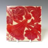 A 20thC pottery Tile, in the style of William de Morgan, the cream ground with ruby lustre floral