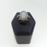 A small opal and diamond cluster Ring, the central cabochon opal approx 8.3mm long, surrounded by