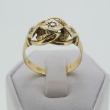 An 18ct yellow gold Ring, the scrolling knot front gypsy set three diamond points, hallmarked