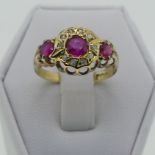 A three stone ruby Ring, the central circular facetted stone, 3.9mm diameter within a surround of