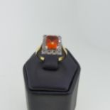 A fire opal and diamond cluster Ring, the central emerald cut opal 8mm x 6mm surrounded by twelve