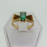 A small emerald Ring, the emerald cut stone 5.9mm long, four claw set in a modernist 18ct gold shank