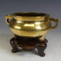 An early 20thC Chinese polished brass tripod Censer, of simplistic form and looping handles,