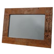 An Arts and Crafts copper wall Mirror, rectangular hammered frame decorated in relief with heart and