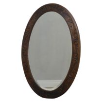 An Arts and Crafts carved oak wall Mirror, foliate scroll frame encasing bevelled plate, of large